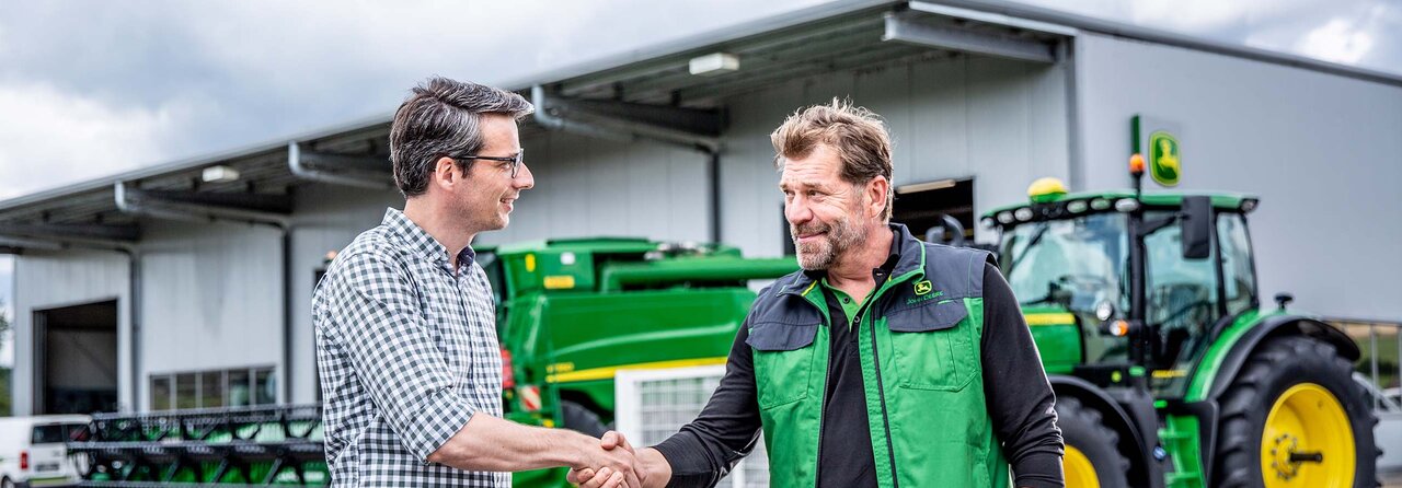 A John Deere employee and a happy customer shaking hands