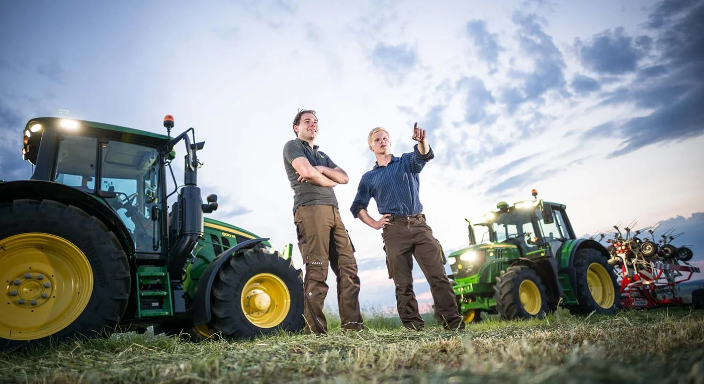 A customer and a dealer represantative on a hay field discussing